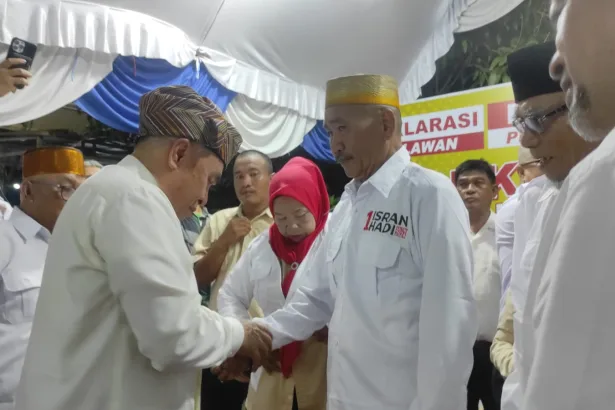 Calon Gubernur Kaltim Isran Noor memakaikan seragam relawan Isran-Hadi kepada Daeng Tunru pada Senin malam (14/10/2024).